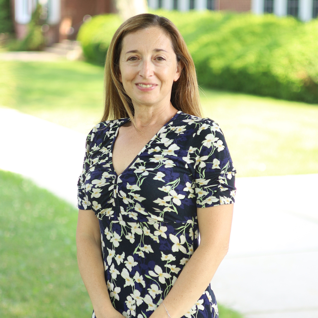 Woman stands smiling in front of camera 
